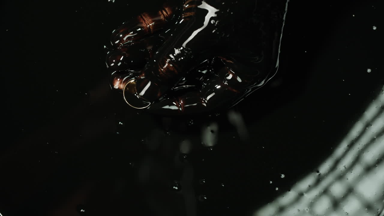 Hand holding coin in black oil