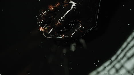 hand holding coin in black oil