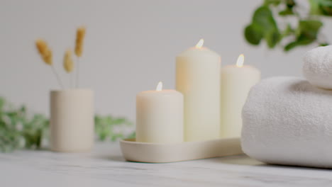 still life of lit candles with dried grasses green plant and soft towels as part of relaxing spa day decor 1