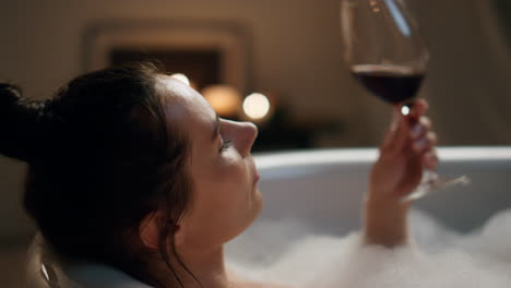 sensual model sipping wine glass resting bathroom. woman touching skin chilling