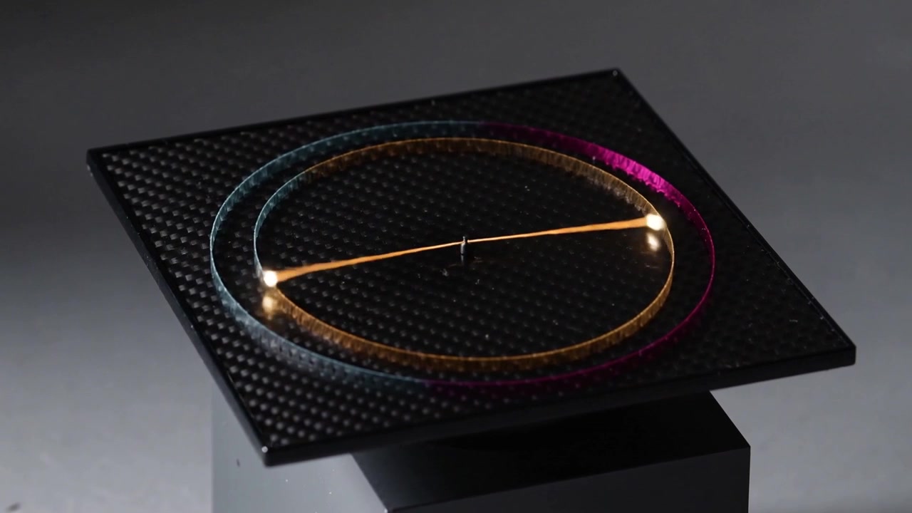 Pivot activating, glass ring with metal arm rotating clockwise on studio table, showing bead glints