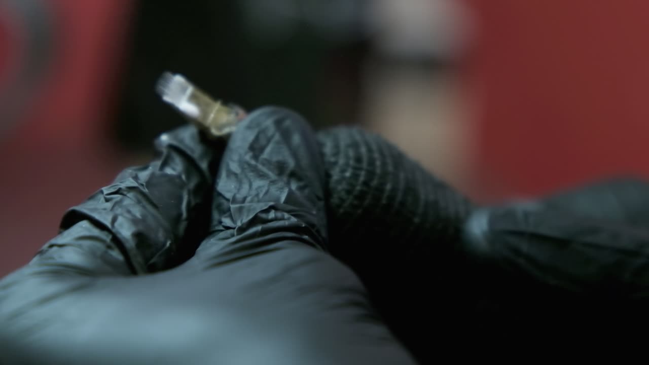 Close up of Tattoo needle being plugged into tattoo gun in slow motion. Turned on and starts spitting white ink.