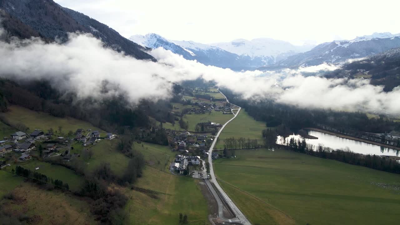 Nuvole basse che incombono sulla valle con una strada al centro e circondata da montagne