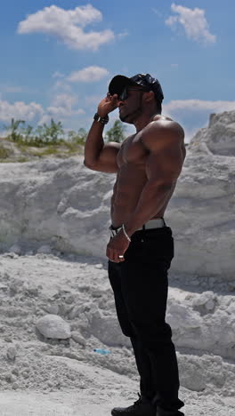 fit worked-out man walking out with blue sky. full length view of the handsome muscular strong man with naked torso posing outdoor. vertical video