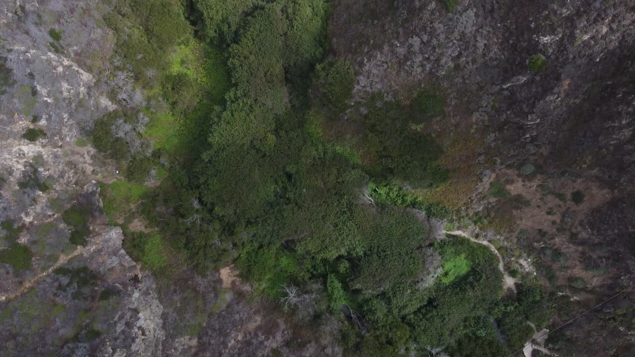 Topdown drone flyover of mountains and a bridge leading to the seas