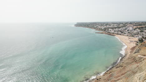 drone shot over a cliff revealing the beach at luz portugal