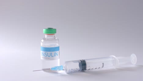 Close-up-of-insulin-vial-and-syringe-on-grey-background-with-copy-space,-slow-motion