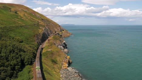 Train-riding-on-hillside-along-coast-on-sunny-day