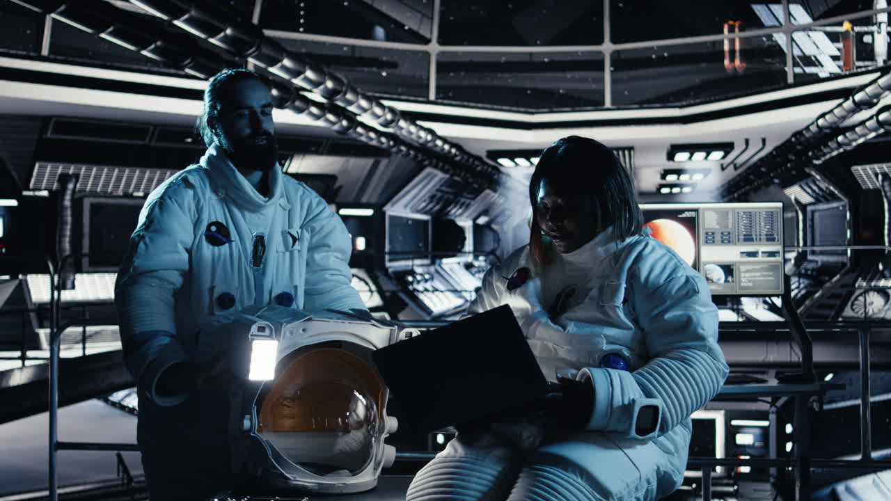 Astronaut reviewing onboard analytics on laptop before stepping out of station