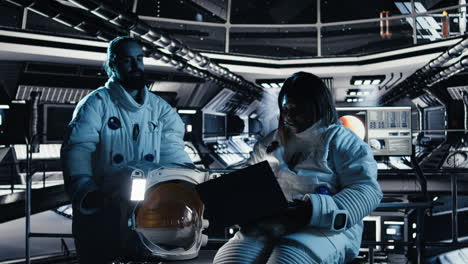 astronaut reviewing onboard analytics on laptop before stepping out of station