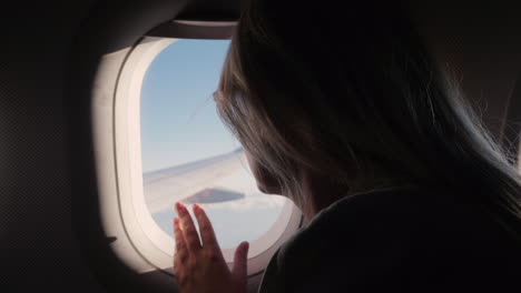 Silhouette-Einer-Frau-Schaut-Aus-Dem-Bullauge-In-Den-Himmel-Und-Der-Flügel-Des-Flugzeugs-Im-Flug-Genießt-Das