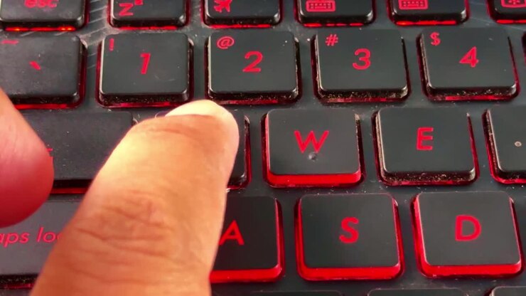 Finger typing action on illuminated keyboard in "Q" button, reflecting modern technology and communication