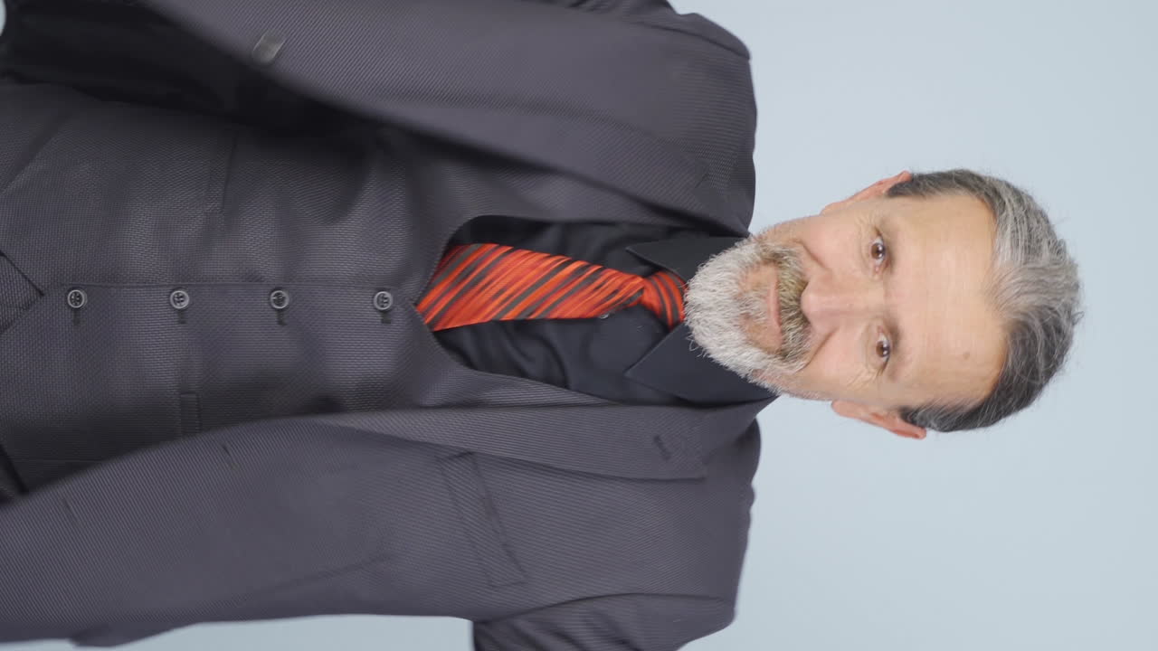 video vertical de un viejo hombre de negocios haciendo corazón a la cámara.