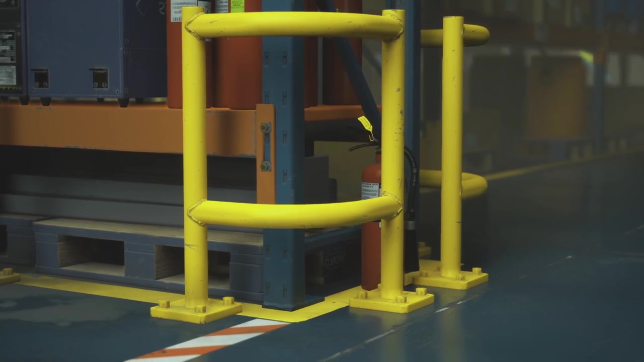 Bright yellow safety barriers protect equipment in an active warehouse zone
