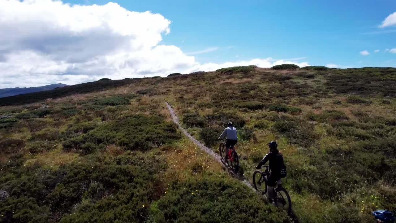 dron siguiendo a ciclistas de montaña subiendo una montaña rumbo a la cima