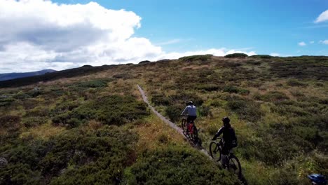 Drohne-Folgt-Mountainbike-Fahrern,-Die-Einen-Berg-Hinauf-Zum-Gipfel-Fahren