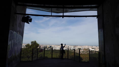 Woman-holding-a-phone-with-Lisbon-in-the-background---slow-motion