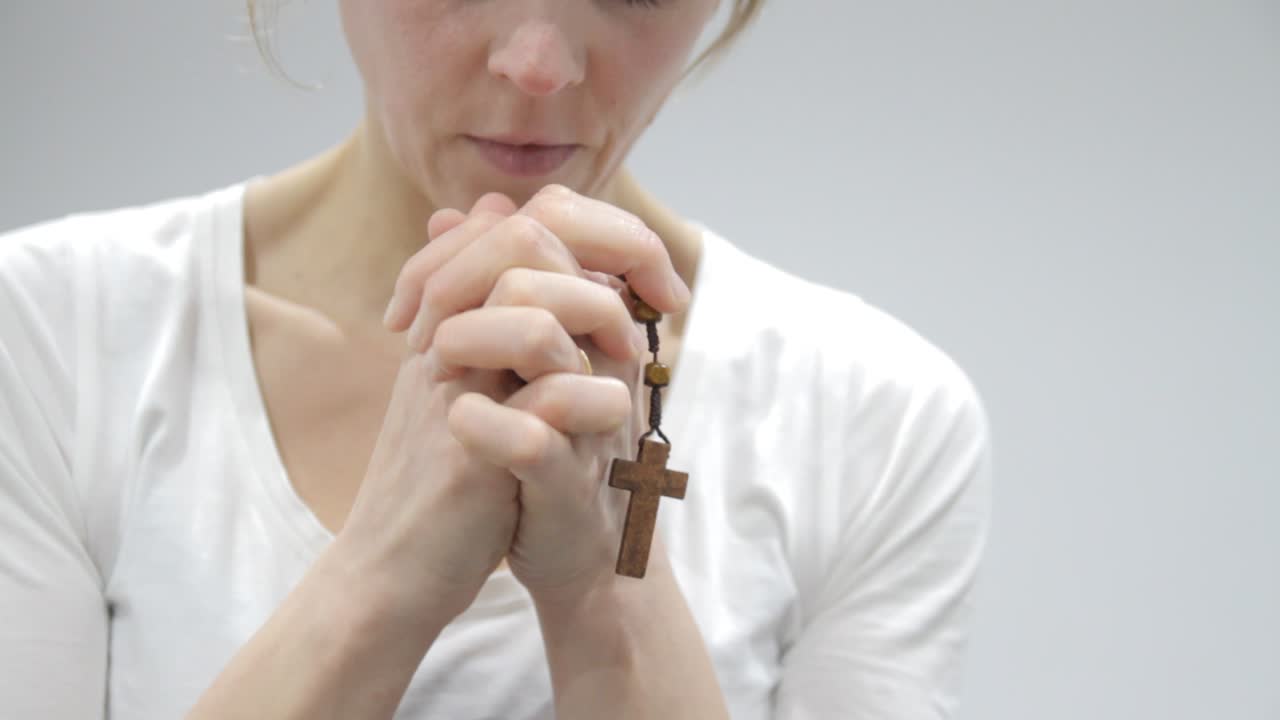 밝은 배경에서 손에 십자가를 들고 기도하는 여자 스톡 비디오