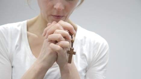 woman praying holding cross in her hands on light background stock video