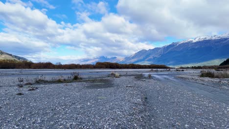 expansive riverbed with distant mountains under a partly cloudy sky. calm, natural setting with soft lighting and minimal movement