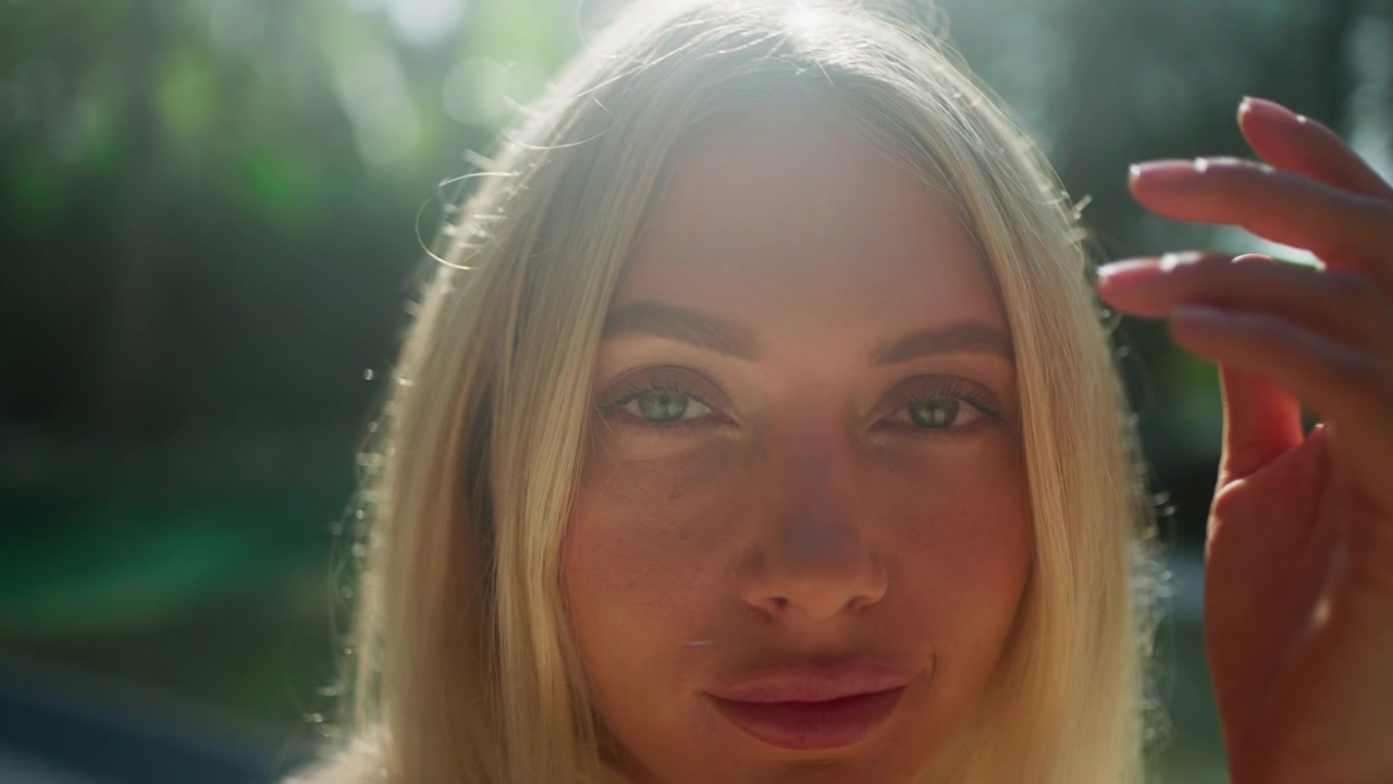 Gesto civettuolo di una bella modella caucasica, giovane e bionda, che si sposta i capelli dietro l'orecchio accanto a una piscina di lusso - Dolly, carrellata in avanti, primo piano, bassa profondità di campo, slow motion.