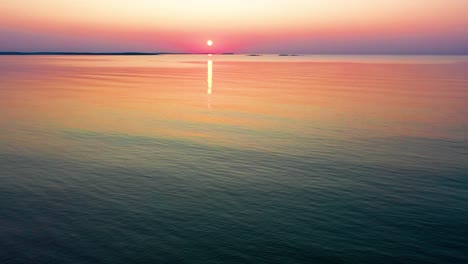 aerial drone view of colorful beach sunrise in saco, maine with bright colors reflecting off calm rippling ocean waves along the new england atlantic coastline