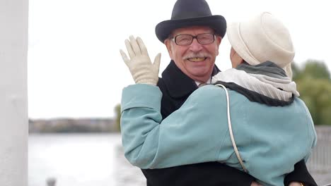 an elderly couple embracing outdoors by a lake
