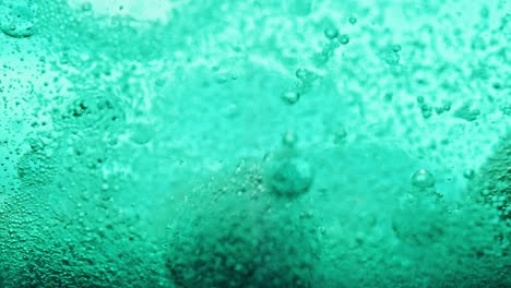 macro shot of blue bubbles dripping and moving around in bright blue water