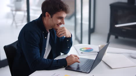 Business-man-looking-documents-on-laptop.-Smiling-guy-analyzing-financial-charts