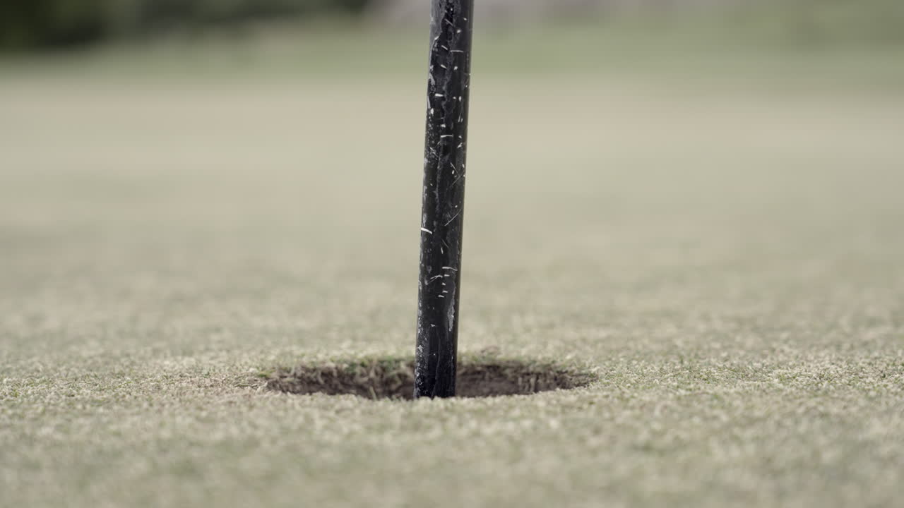 Golf ball rolling into the hole on green