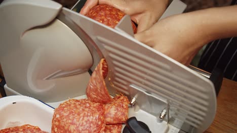 chef slices salami on meat slicer machine