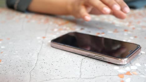 a person reaches for their phone on a table.