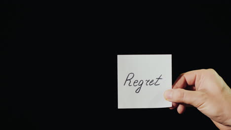 hand holds burning paper with inscription regret