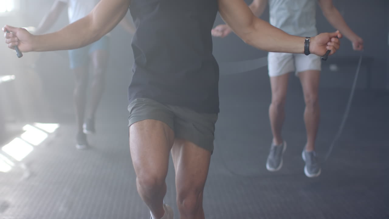 Jumping rope, men exercising in gym, focusing on fitness and cardio workout
