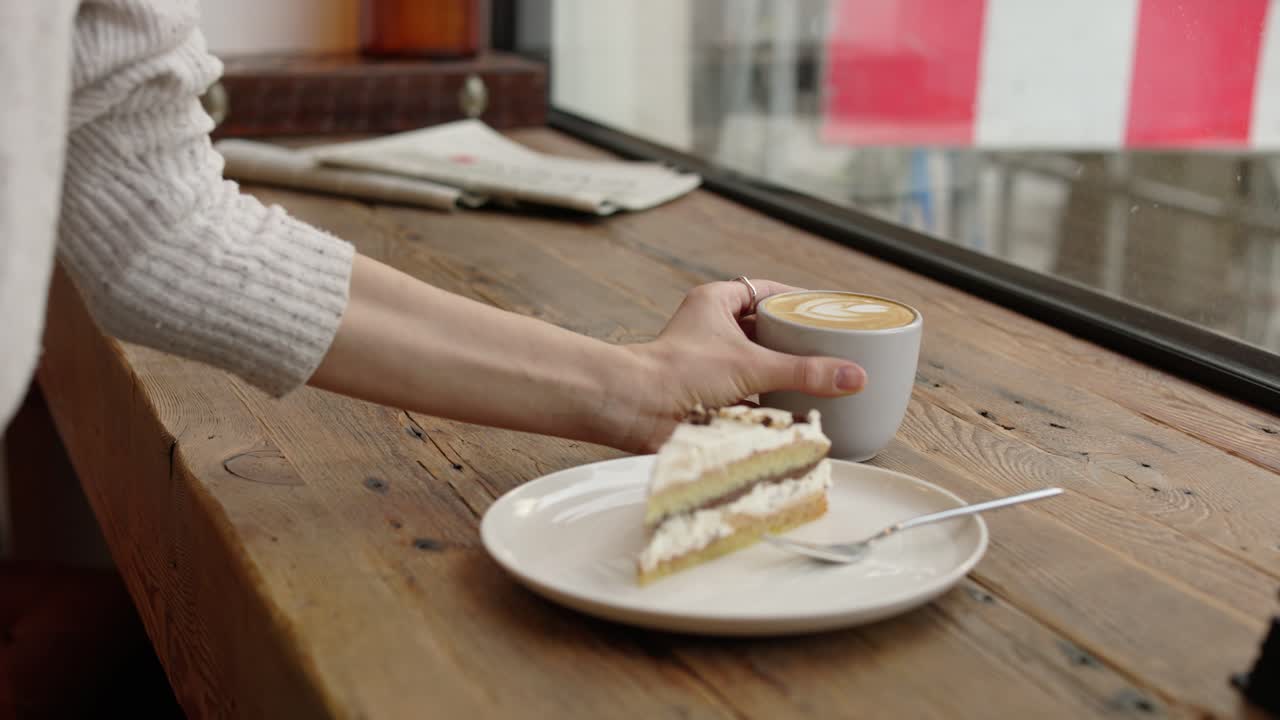 mujer disfrutando de café y pastel en un café junto a la ventana
