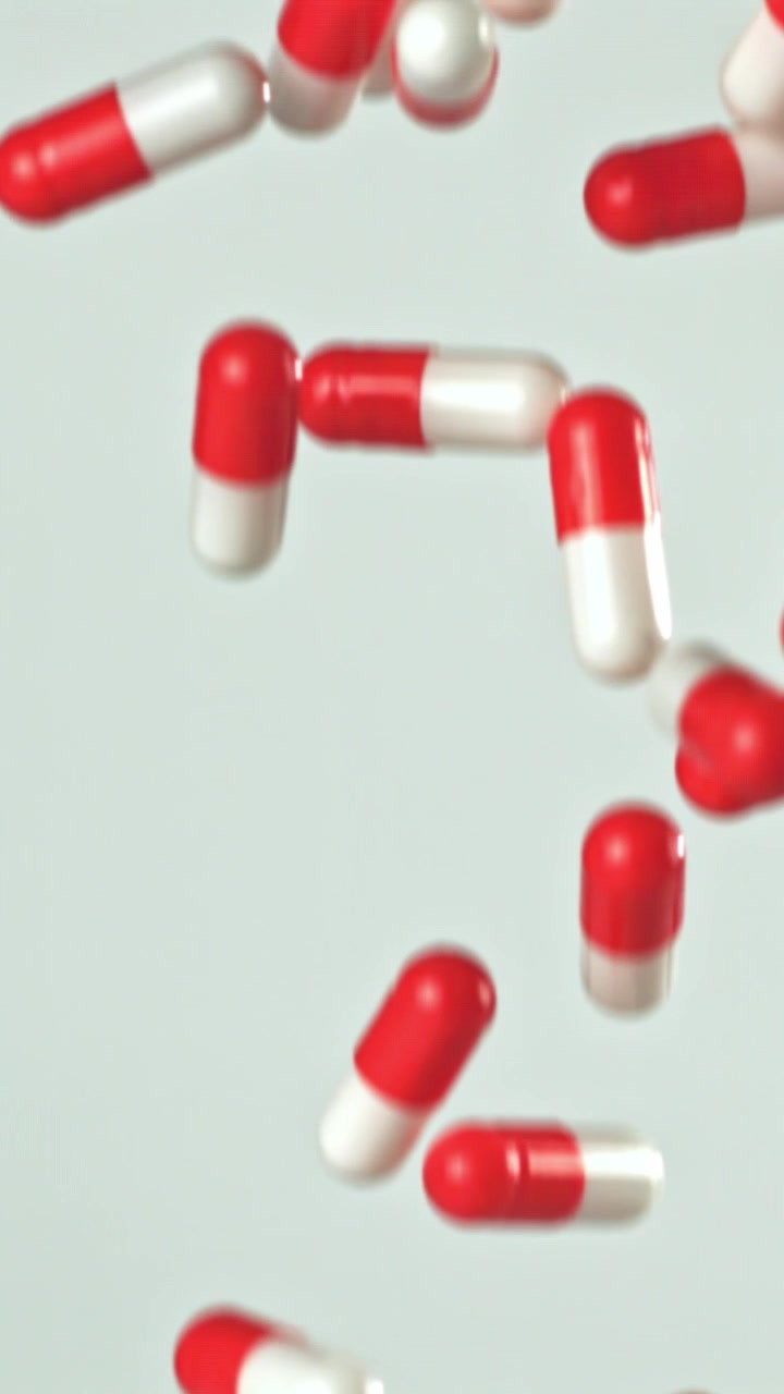 Capsule farmaceutiche rosse e bianche che cadono al rallentatore