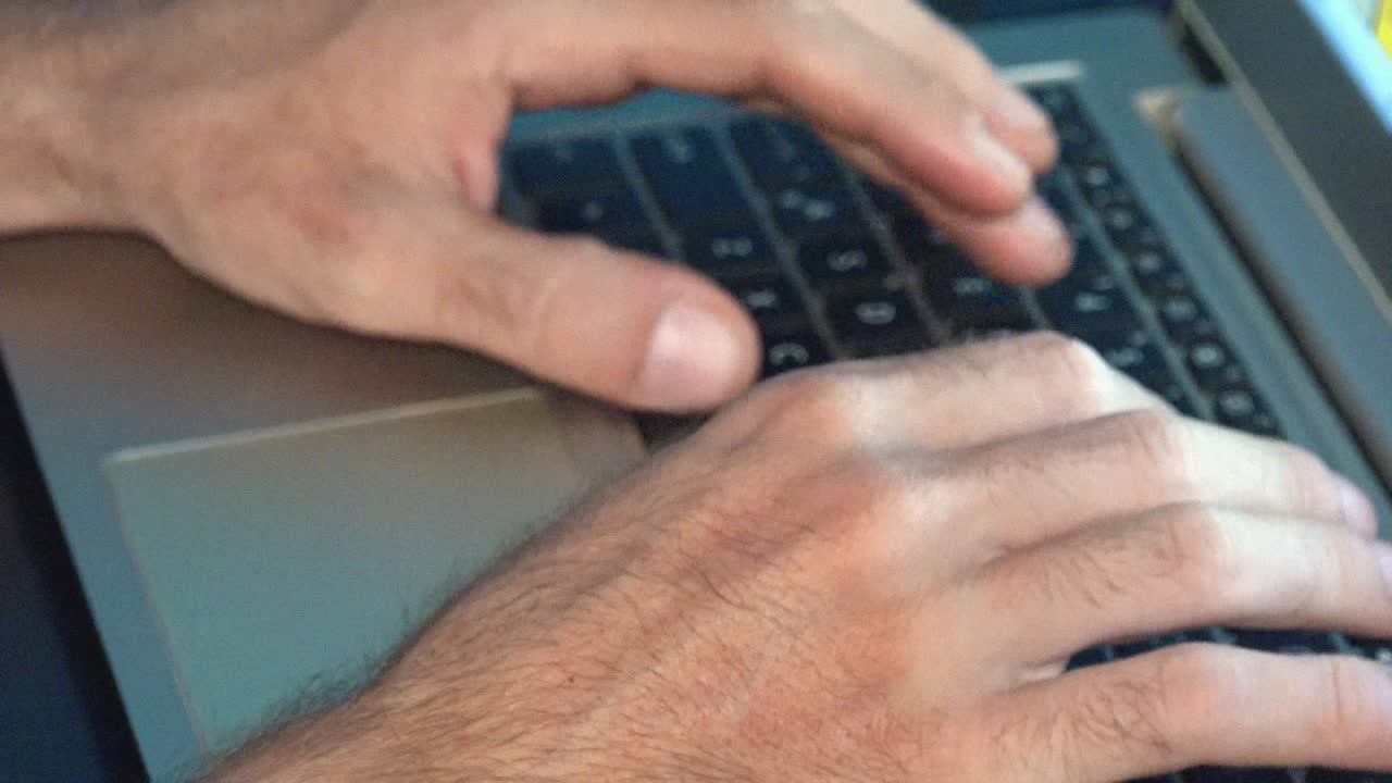 toma cercana de manos masculinas escribiendo en una computadora portátil