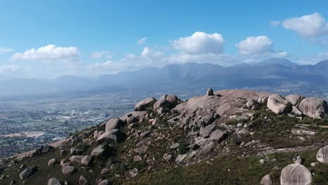 una vista de avión no tripulado de una colina rocosa que se eleva sobre una ciudad en un valle