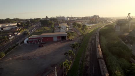 Cargo-train-with-many-wagons-transporting-supplies-on-rails,-aerial-drone-view