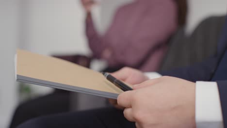 Close-Up-Of-Male-And-Female-Candidates-In-Office-Waiting-For-Job-Interview-