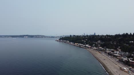disparo de dron que revela lentamente los imponentes rascacielos de seattle desde la playa de alki