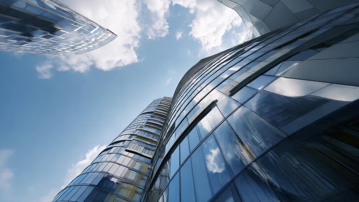 Arquitectura moderna de cristal reflectante con perspectiva ascendente que muestra el diseño elegante y el uso innovador de materiales en rascacielos urbanos sobre un fondo nuboso