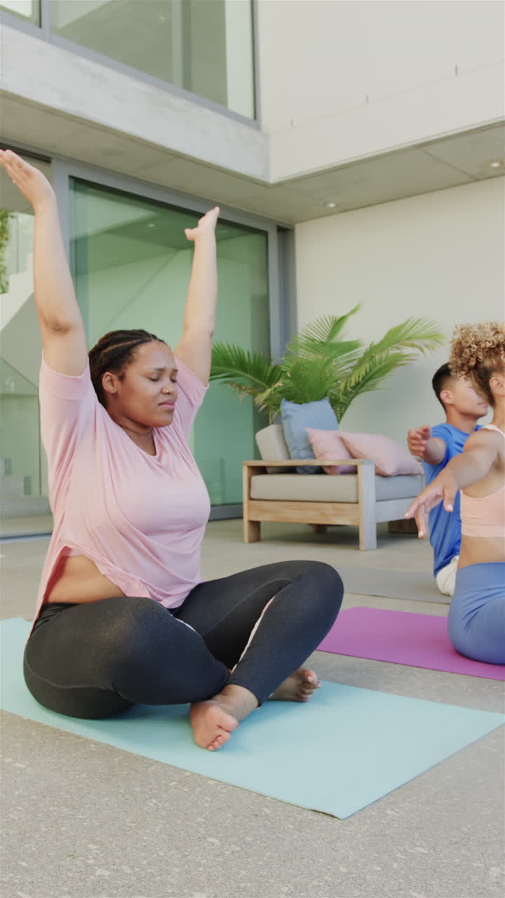 Vertical video: Practicing yoga, group of friends stretching on yoga mats at home patio