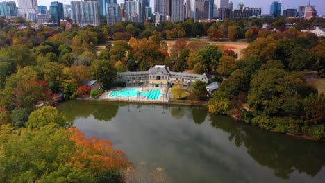 Aerial-drone-shot-flying-over-the-public-swimming-pool-in-Piedmont-Park-with-the-skyline-of-downtown-Atlanta,-Georgia-in-the-background