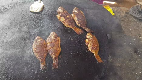 spicy fish being fried in a big cast iron pan