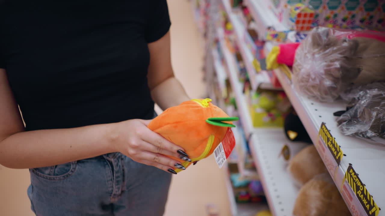 상점 선반에서 활기찬 오렌지색과 초록색 지갑을 뽑는 여성의 위아래 클로즈업, 세부 사항을 관찰하면서, 쇼핑객은 소매 설정에서 세련된 액세서리를 탐색합니다.