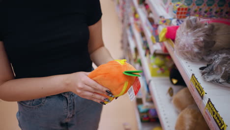 top-down close-up of woman picking vibrant orange and green purse from store shelf while observing details, shopper browses stylish accessories in retail setting