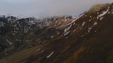 Aerial-landscape-view-of-icelandic-mountain-peaks-covered-in-melting-snow,-on-a-moody-day