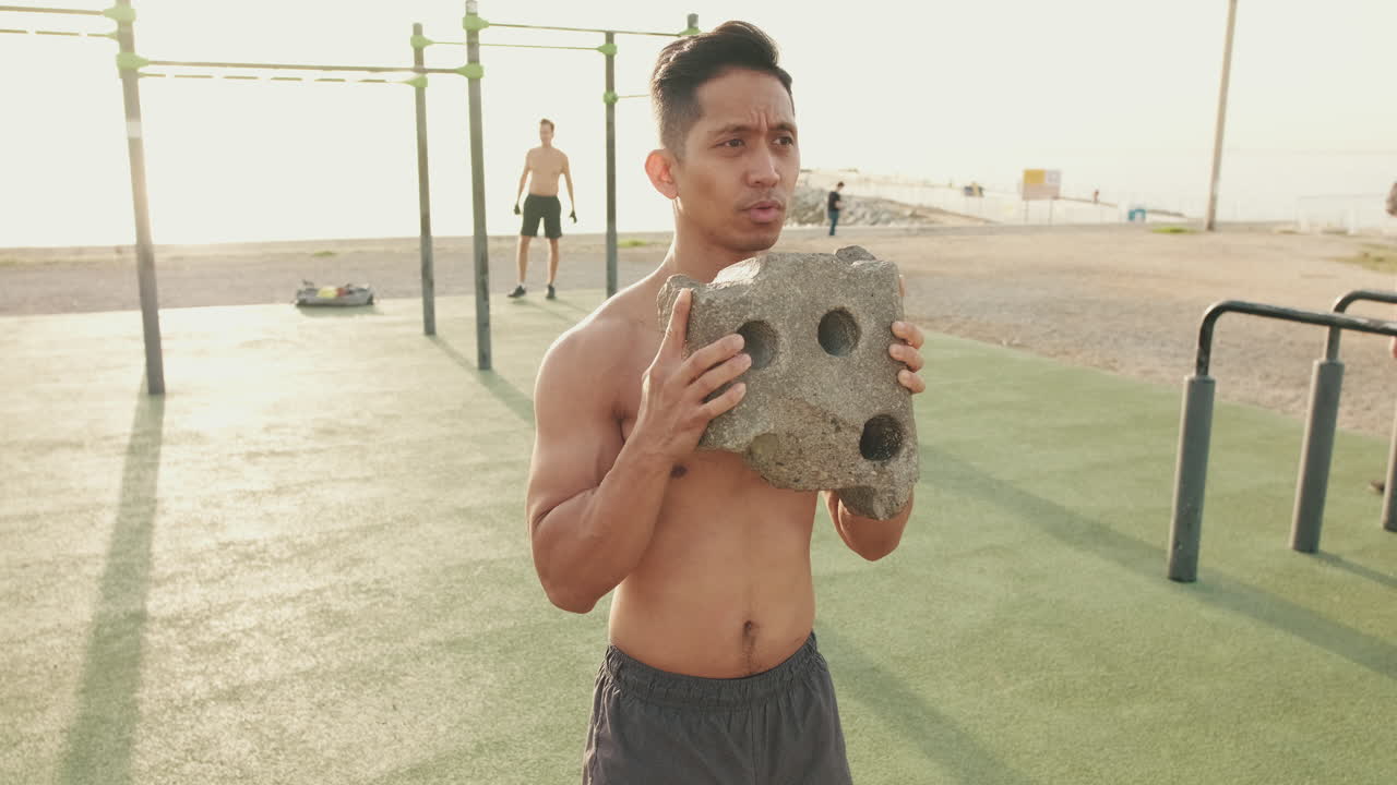 Man doing calisthenics outdoors with stone weights