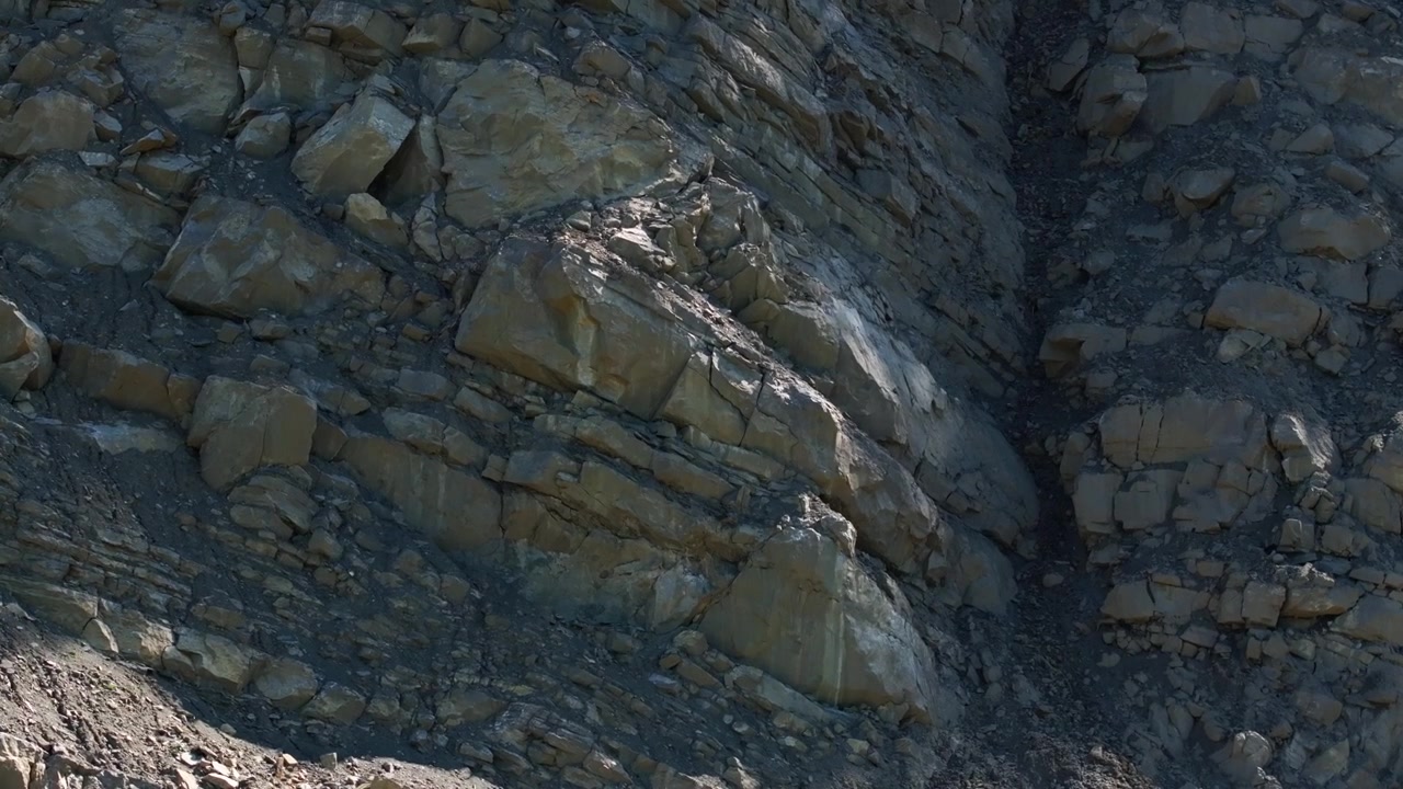 Strati di roccia esposti e detriti sciolti sulla parete ripida di una cava attiva. Il pendio scavato rivela strati geologici, pietra fratturata e depositi minerali grezzi in un sito di estrazione industriale.